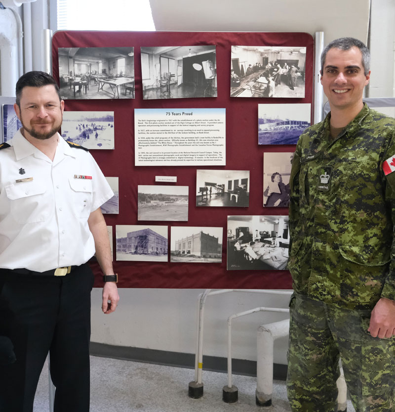 Chief Petty Officer 1st Class (CPO 1) Shawn M. Kent (left) and Warrant Officer Jean-François Lauzé stand in front of a historical diorama at the Operational and Technical Imagery Centre (OPTIC) in Ottawa, ON on 28 January 2020.